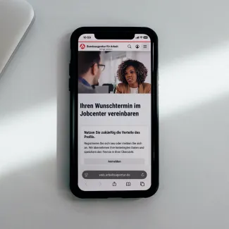 Smartphone mit der geöffneten Terminvereinbarungsseite des Jobcenters.